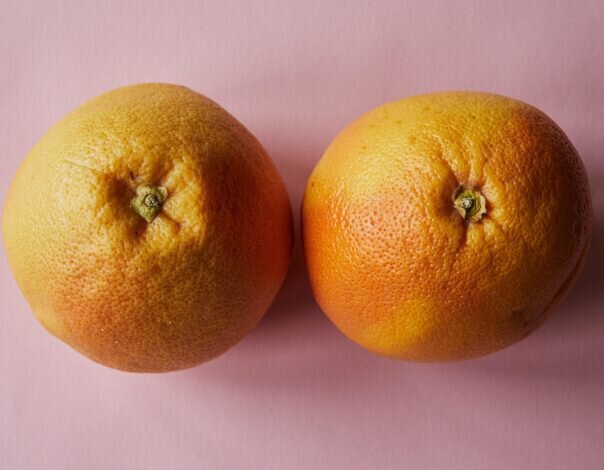 two oranges side by side on pink background