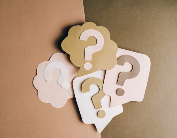 four question marks on separate pieces of pink and brown paper